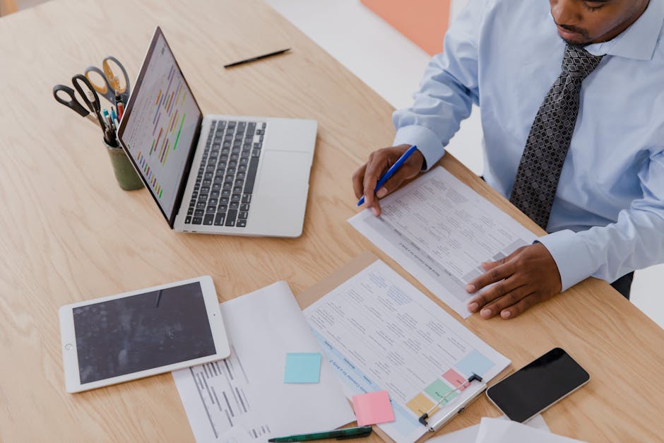 High angle view of a businessman working at a desk with a laptop, tablet, and documents.